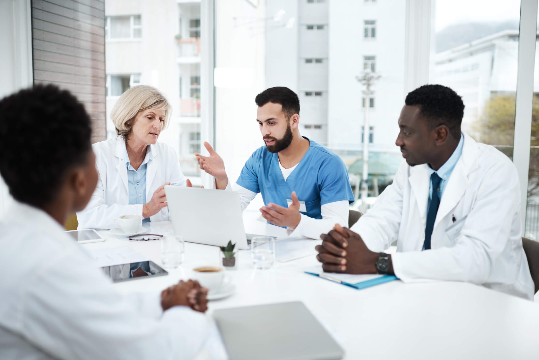 Shot of a group of medical practitioners using a laptop during a meeting in a hospital boardroom physicians in a meeting discussing treatment plans